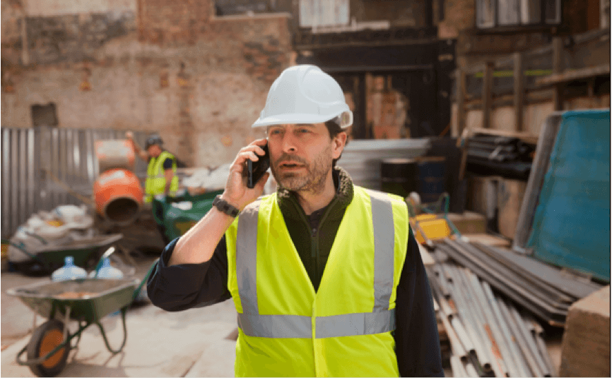 Construction site manager using 5G business broadband on a building site to call a client
